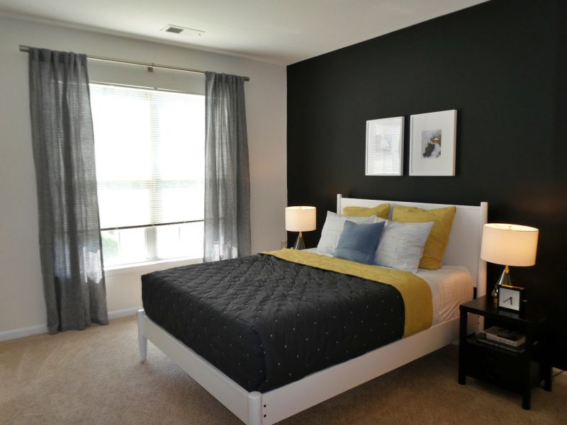 This image shows the bedroom area showcasing the dark tone wall color, elegant bedding, and an overlooking view outside that was ideal for a comfy relaxation.