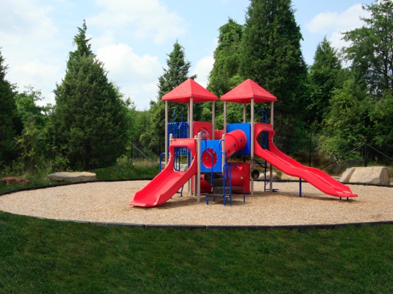 This image shows the expansive view of the community amenities, particularly the spacious playground area with safety equipment featuring the slides and swings.